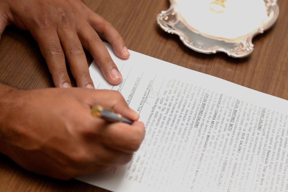 Mão assinando um contrato sobre a mesa