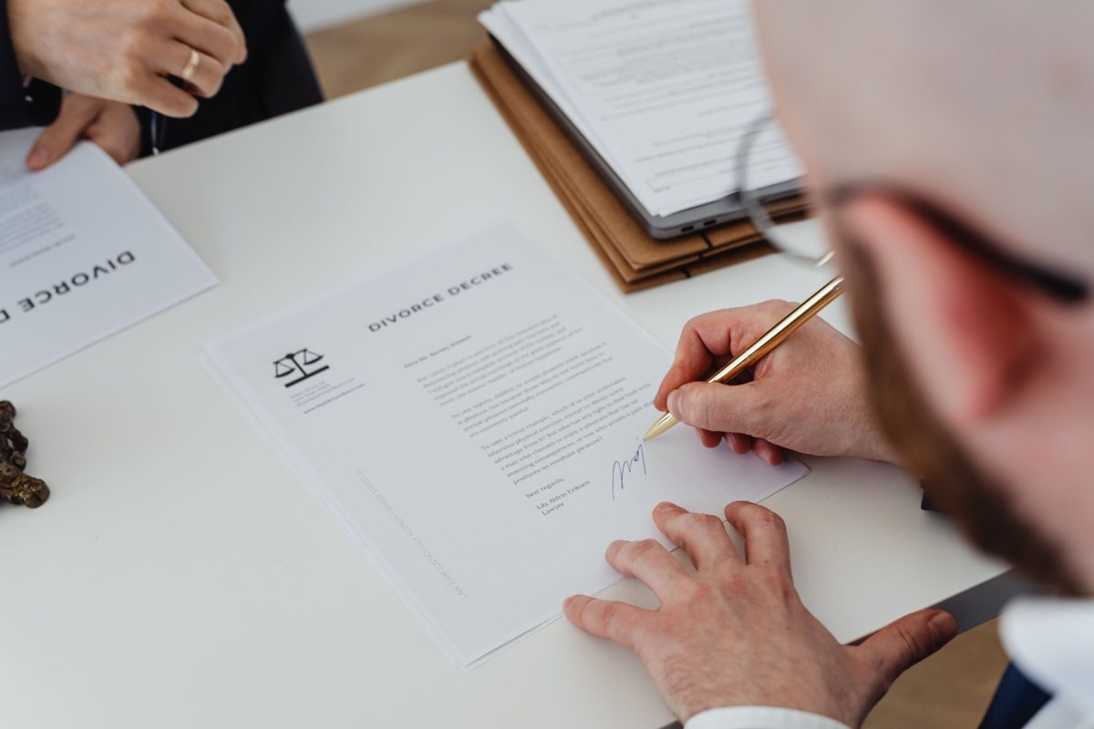 Pessoa assinando um documento sobre a mesa
